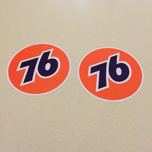 The number 76 in blue in the centre of an orange circular sticker.