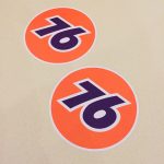 76 UNION RACE CAR STICKERS. The number 76 in blue in the centre of an orange circular sticker.