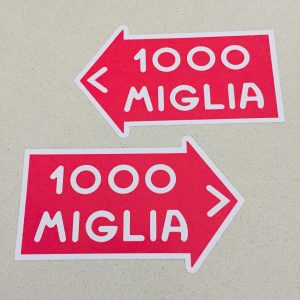 1000 Miglia in white lettering on a red direction of travel arrow with a white border.