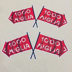 MILLE MIGLIA 1000 FLAG STICKERS. Two crossed flags. 1000 Miglia in white lettering on a red direction of travel arrow with a white border.