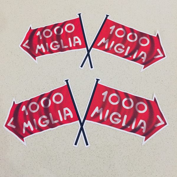 MILLE MIGLIA FLAG STICKERS. Two crossed flags. 1000 Miglia in white lettering on a red direction of travel arrow with a white border.