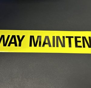 HIGHWAY MAINTENANCE STICKER. Highway Maintenance in black uppercase lettering on a fluorescent yellow sticker.