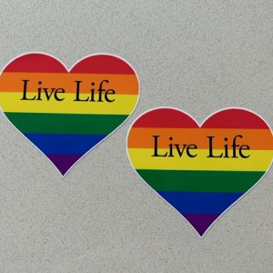 LGBTQ+ LIVE LIFE HEART STICKERS. Live Life in black overlays a heart made up of six horizontal stripes of colour. Red, orange, yellow, green, blue and violet.